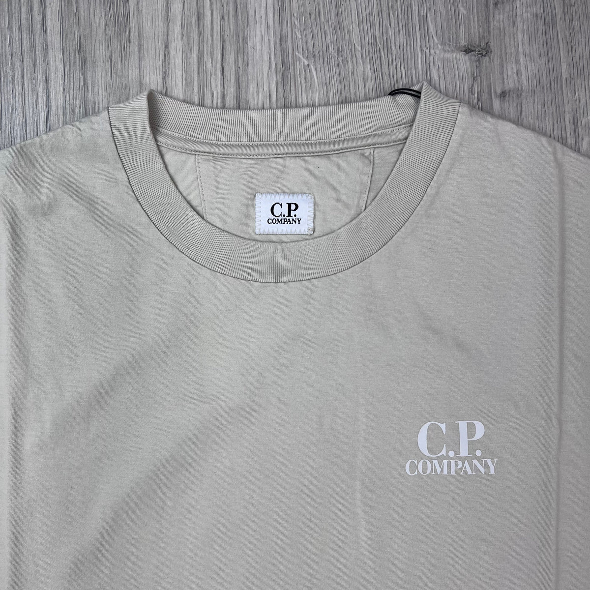Close up view of the crewneck collar and logo patch on a CP Company 30/1 Jersey Sailor T-Shirt in Silver Birch.