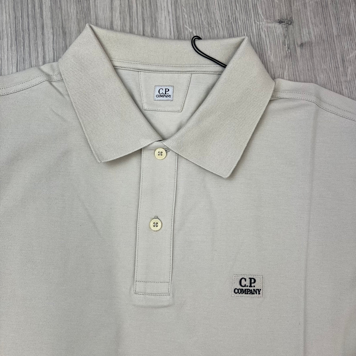 Close up view of the ribbed collar and two-button placket on a CP Company Long Sleeve Stretch Piquet Polo Shirt in Silver Birch.