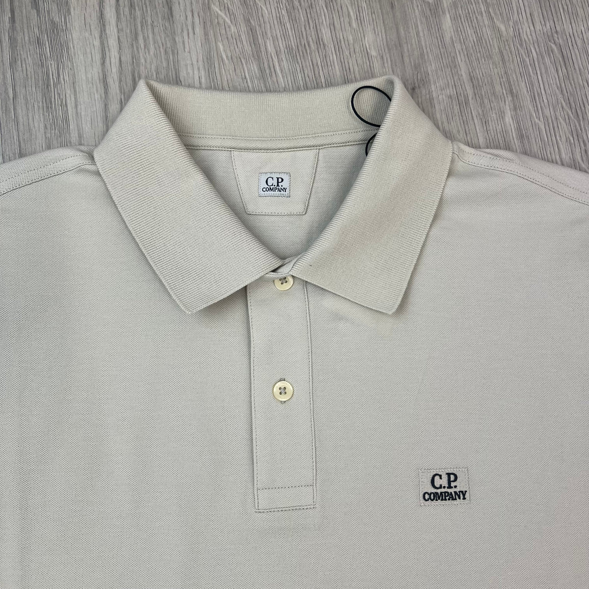 Close up view of the polo collar and two-button placket on a CP Company Stretch Piquet Polo Shirt in Silver Birch.