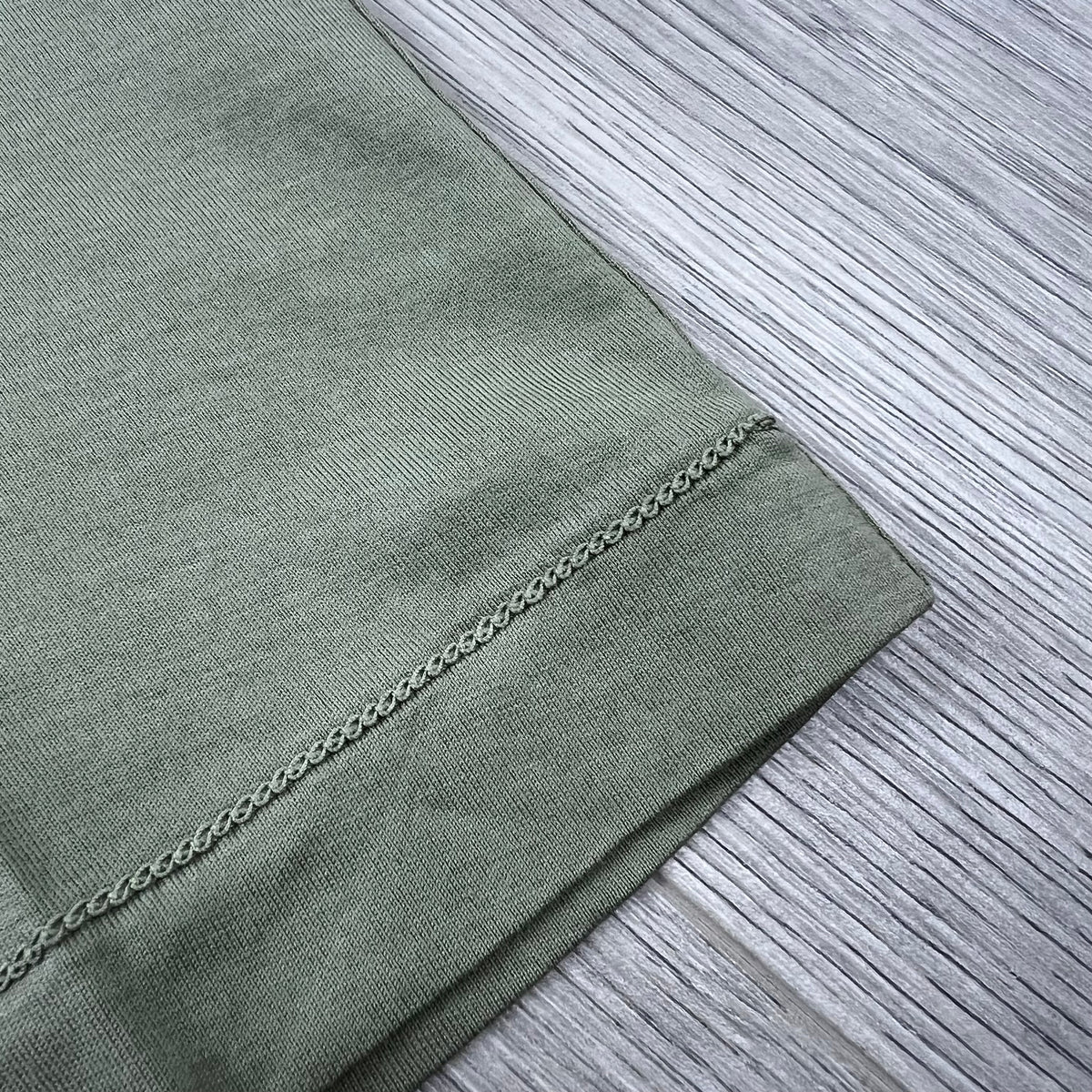 Front view of the chain stitching on the hem of a Stone Island 30/1 Patch T-Shirt in Laurel Green.