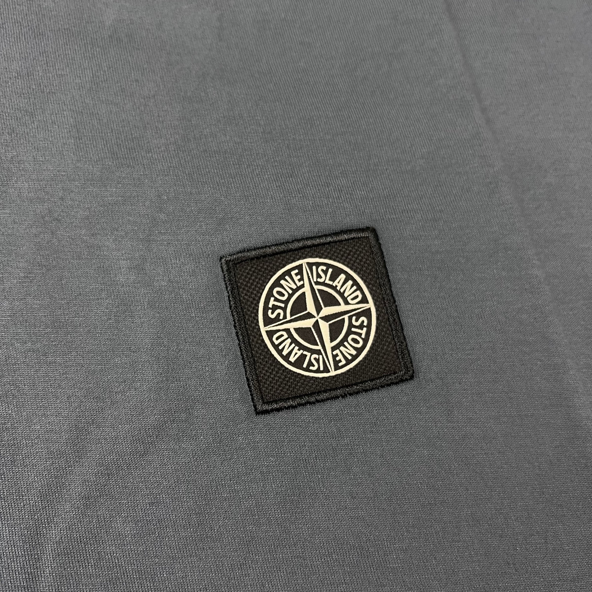 Close up view of the Compass logo on the Stone Island 30/1 Patch T-Shirt in Slate Blue.