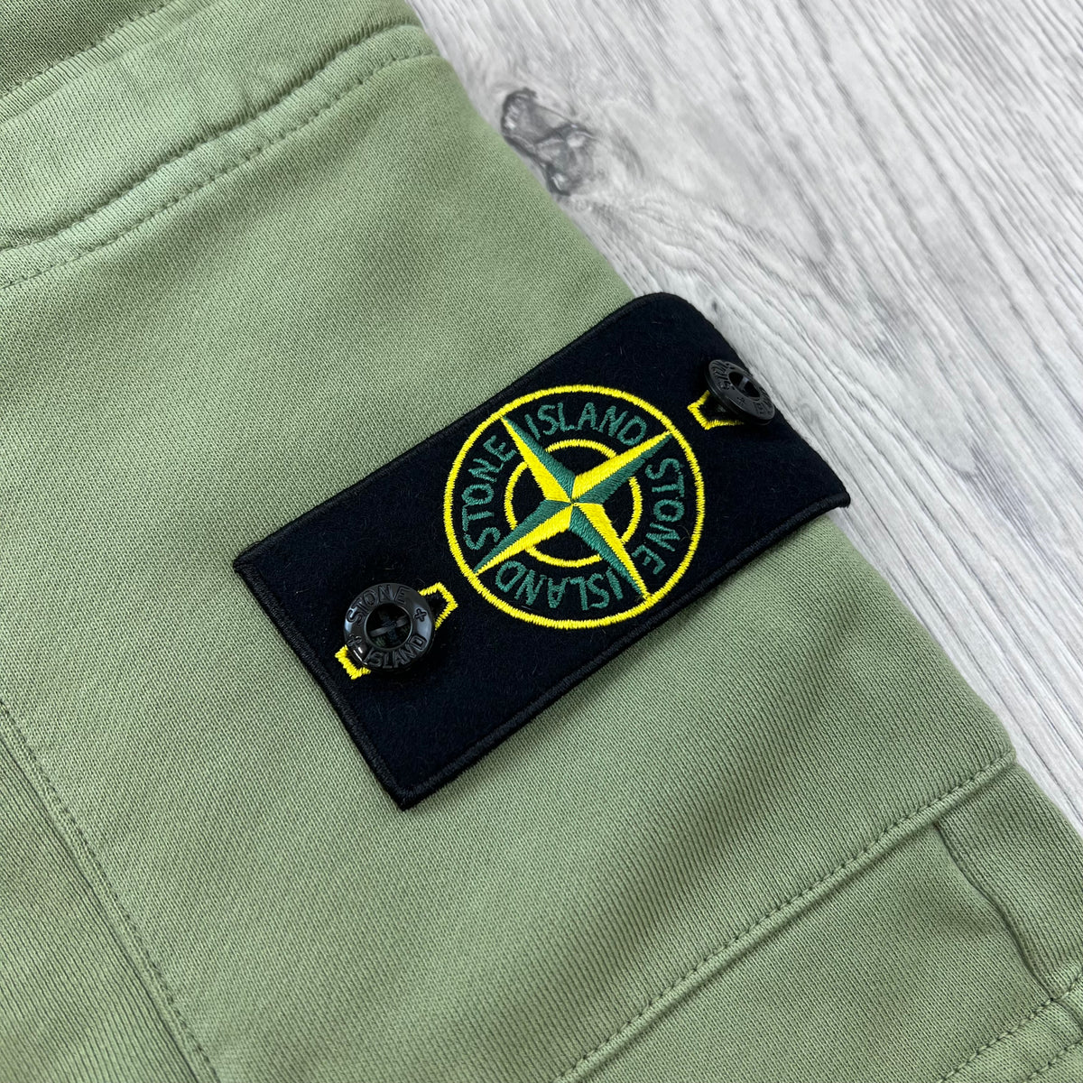 A close up view of the badge on the Stone Island Jersey Shorts in Laurel Green.