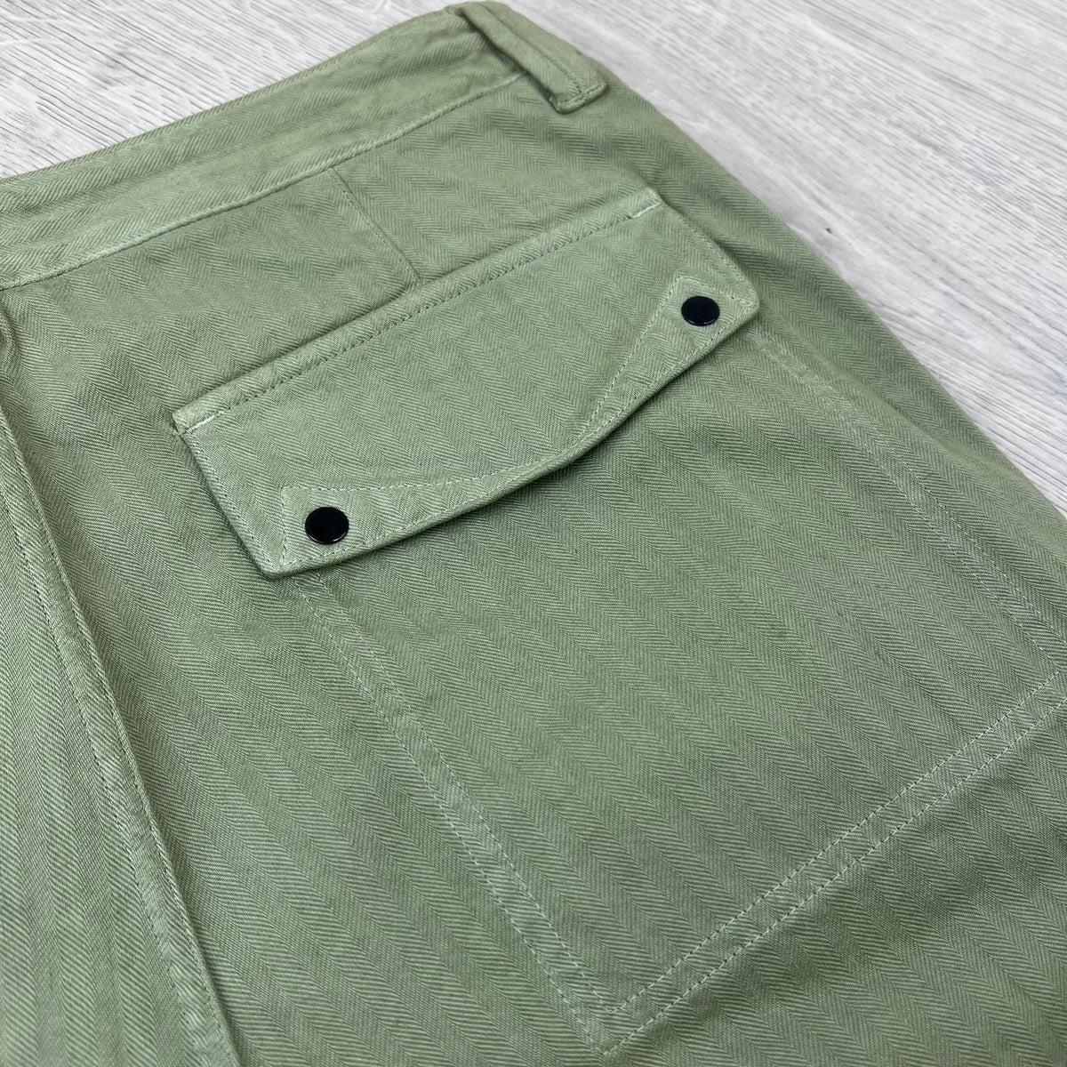 A close up view of back patch pocket on the Stone Island Cotton Herringbone Chino Trousers in Laurel Green.