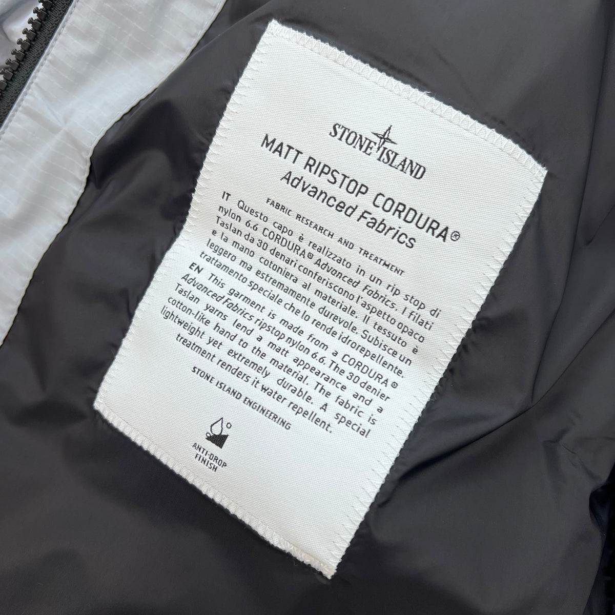A close up view of the engineering label on a Stone Island Matt Ripstop CORDURA® Down Jacket in Ash Grey.