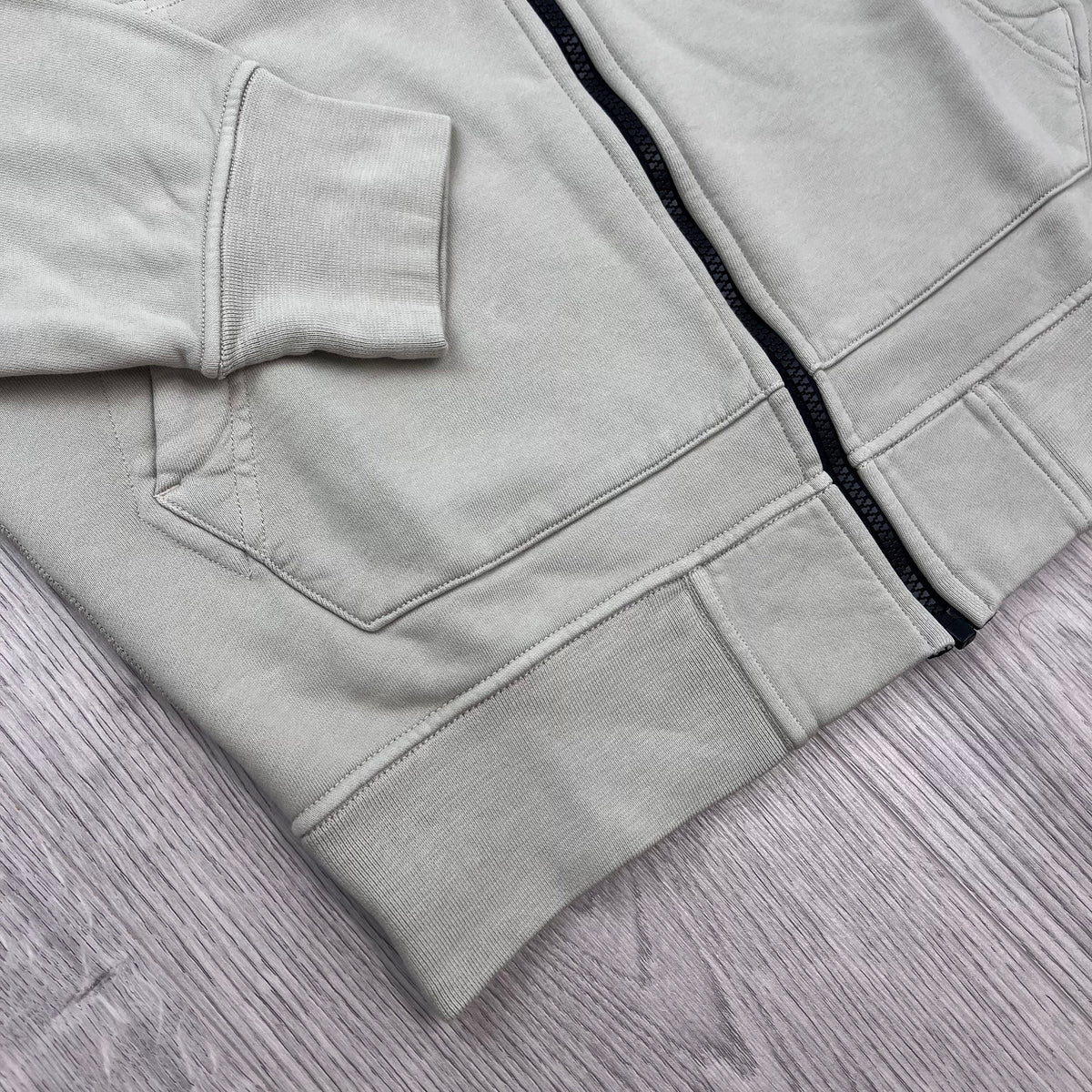 A close up view of the elasticated hem and cuff on the Stone Island Zip Hoodie in Sand.