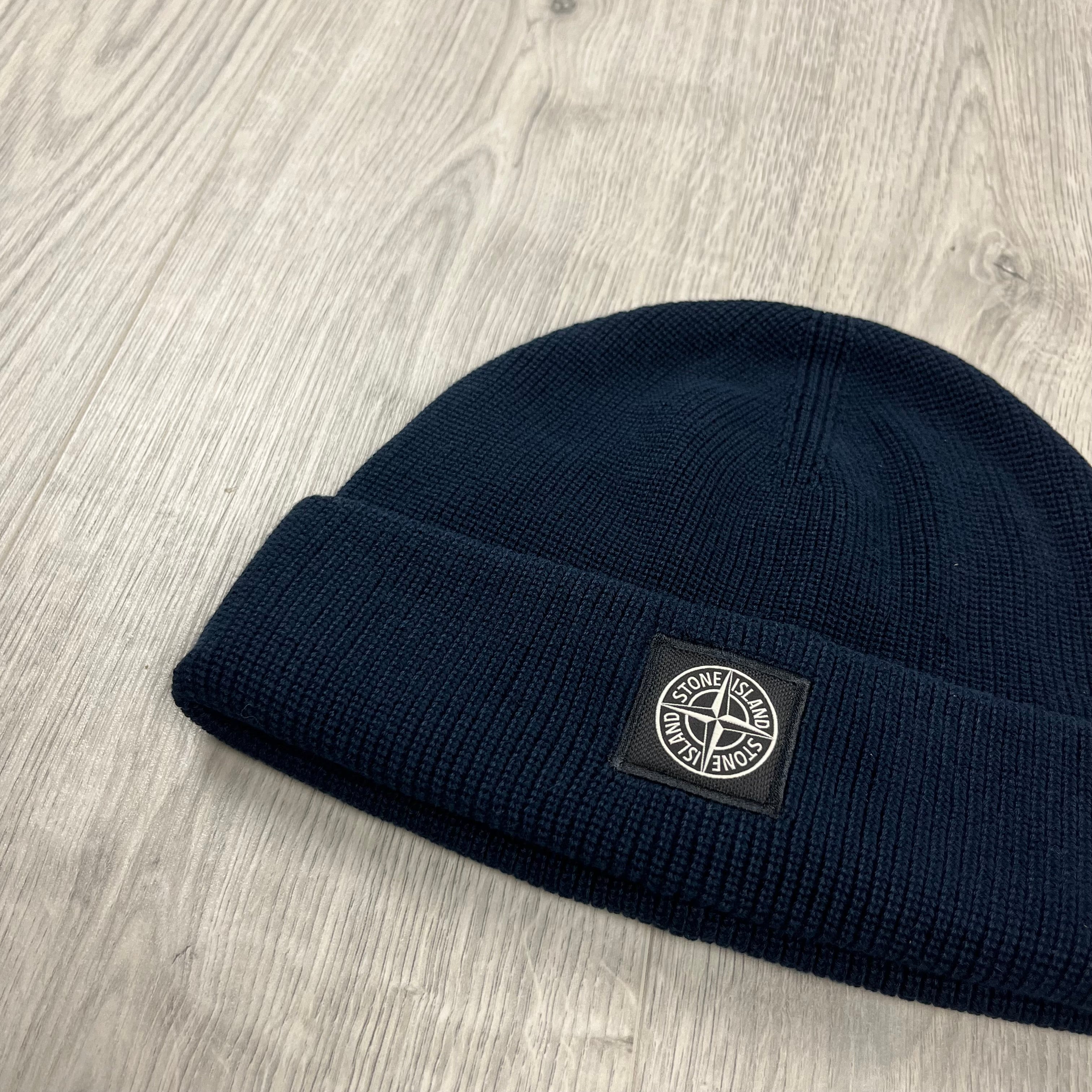 Men's Stone Island beanie close up with a flat ribbed cuff and compass patch logo on the front. On sale at Open Attire.