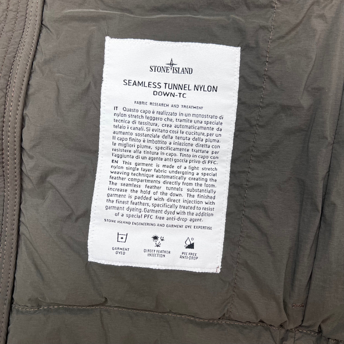 A close view of the engineering label inside a Stone Island Seamless Tunnel Nylon Down-TC Down Gilet in Coal Grey. 