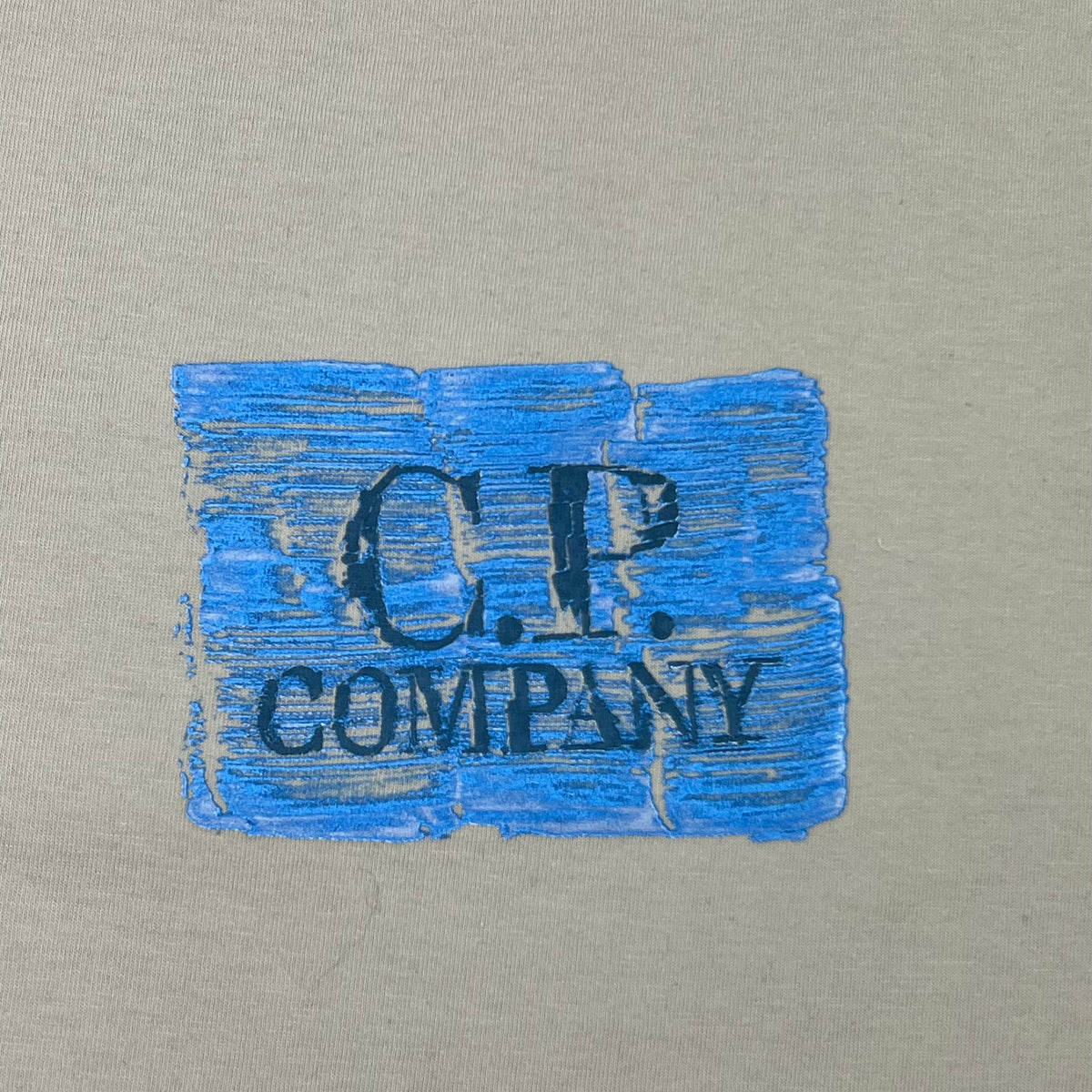 Close up view of the small printed logo on a CP Company 30/1 Jersey Graphics T-Shirt in Silver Birch. 