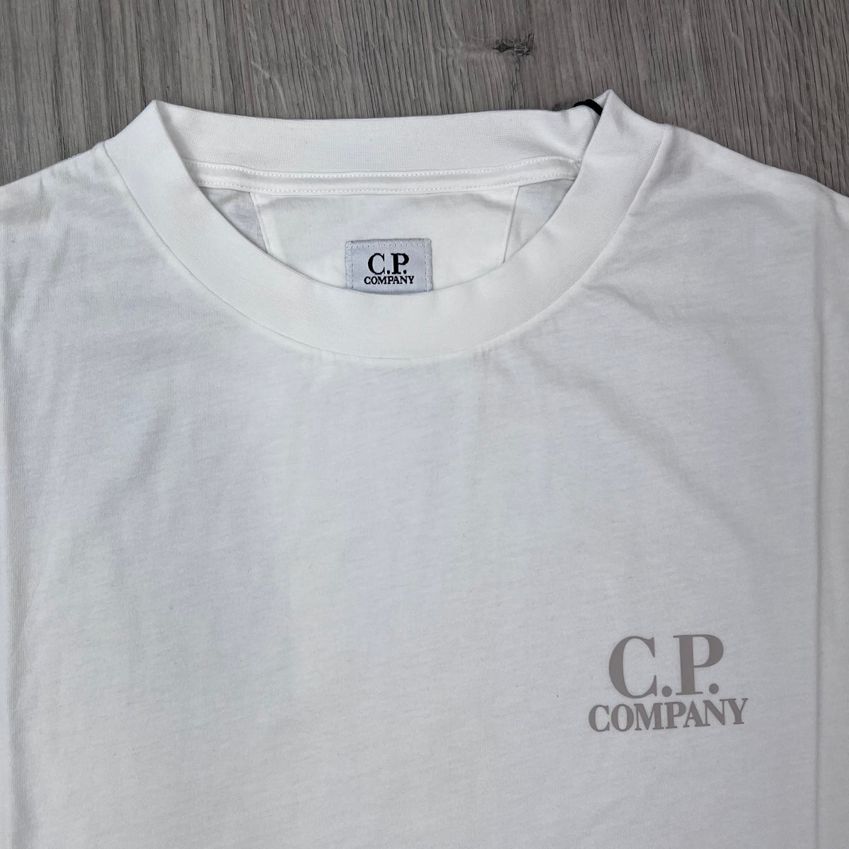 Close up view of the crewneck collar on a CP Company 30/1 Logo T-Shirt in Gauze White. 