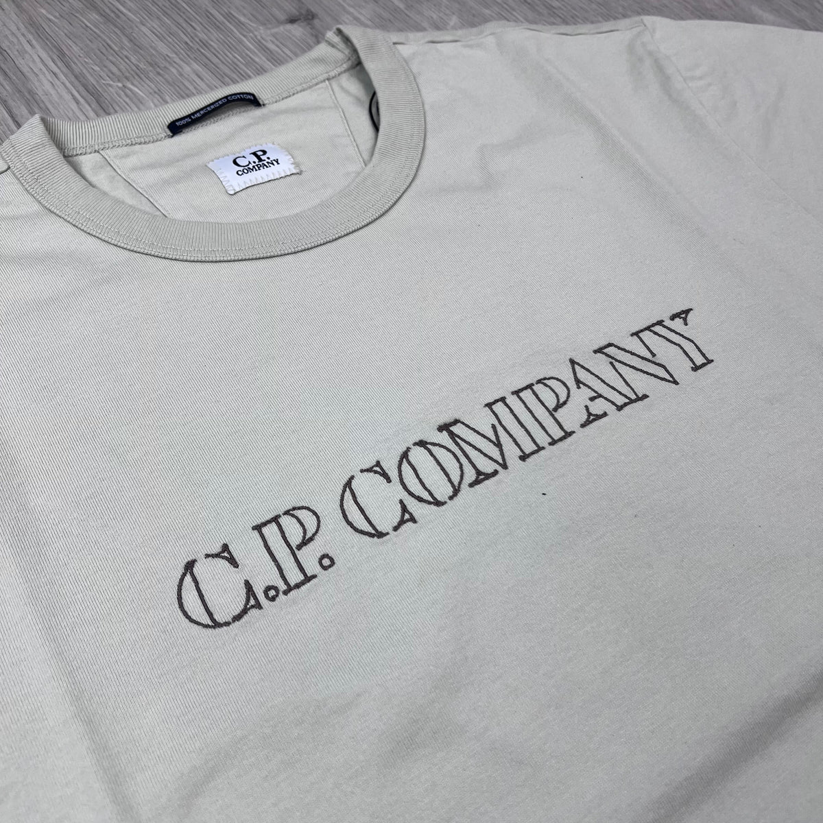 Angled view of the embroidered design on the CP Company 30/2 Jersey Logo T-Shirt in Silver Birch. 