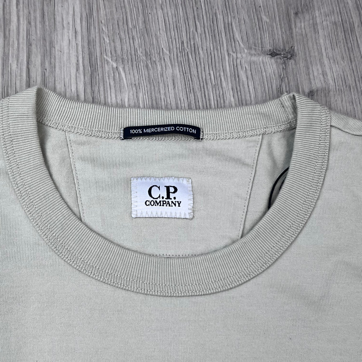 Close up view of the crewneck collar and neck label on the CP Company 30/2 Jersey Logo T-Shirt in Silver Birch. 