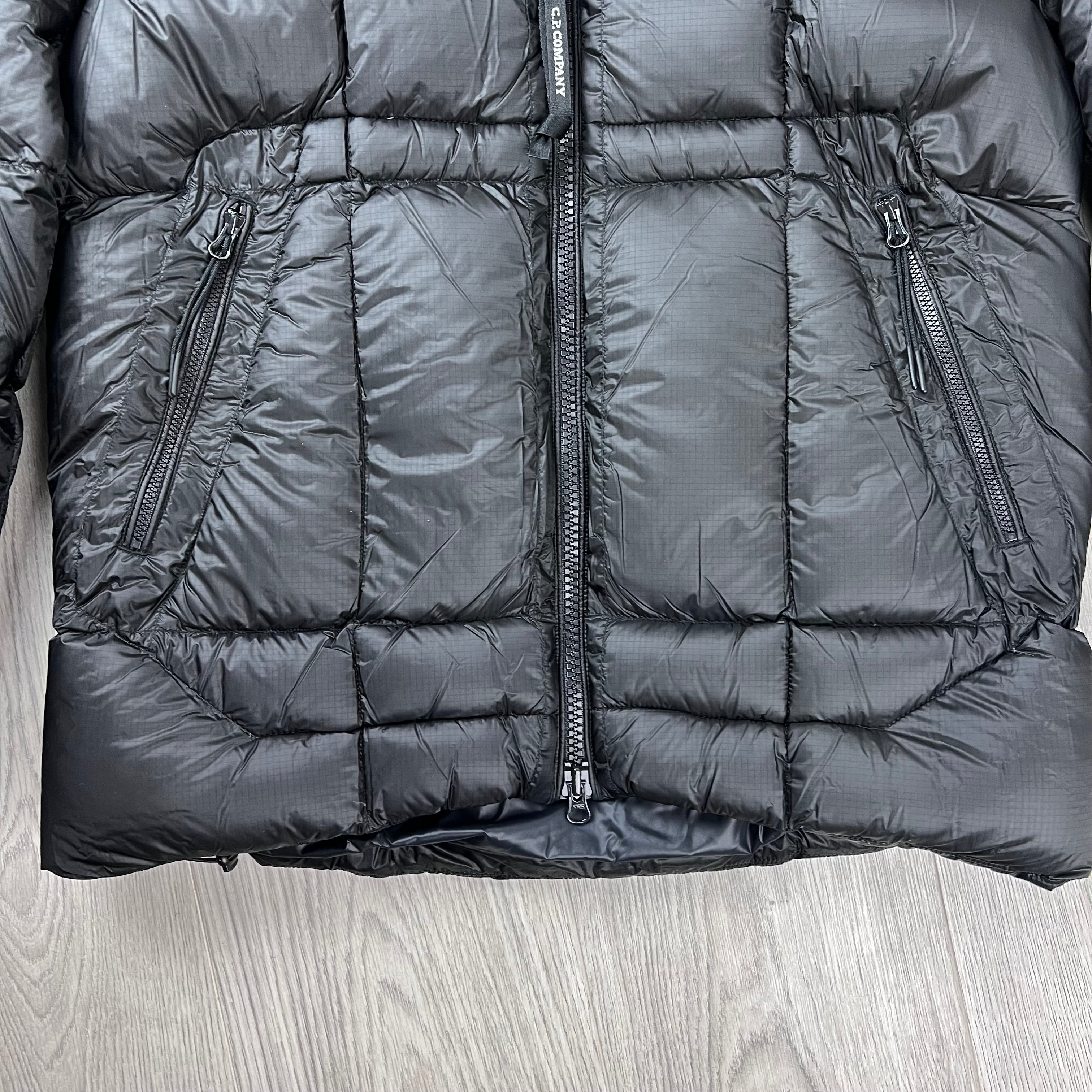 The front view of the hem and pockets on the CP Company D.D. Shell Hooded Down Jacket in Black. 
