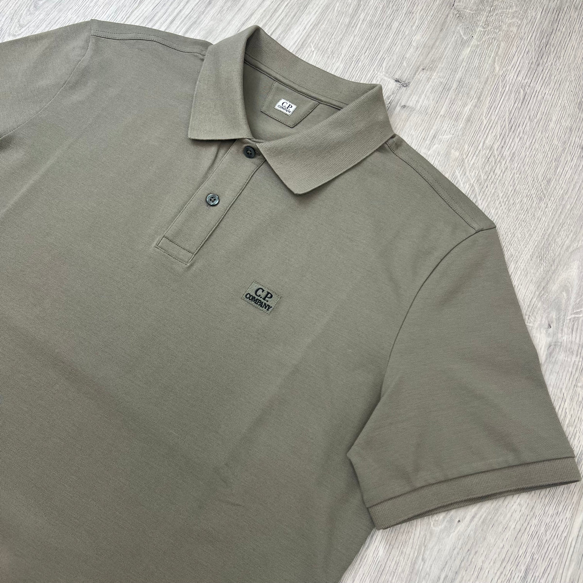 Angled view of the short sleeves and collar on a CP Company Stretch Piquet Polo Shirt in Fallen Rock.