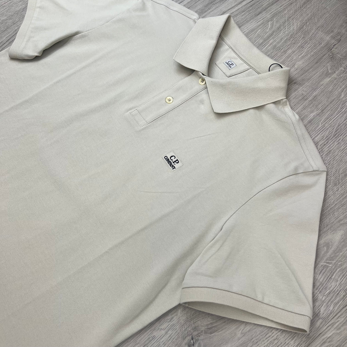 Angled view of the short sleeves and collar on a CP Company Stretch Piquet Polo Shirt in Silver Birch.