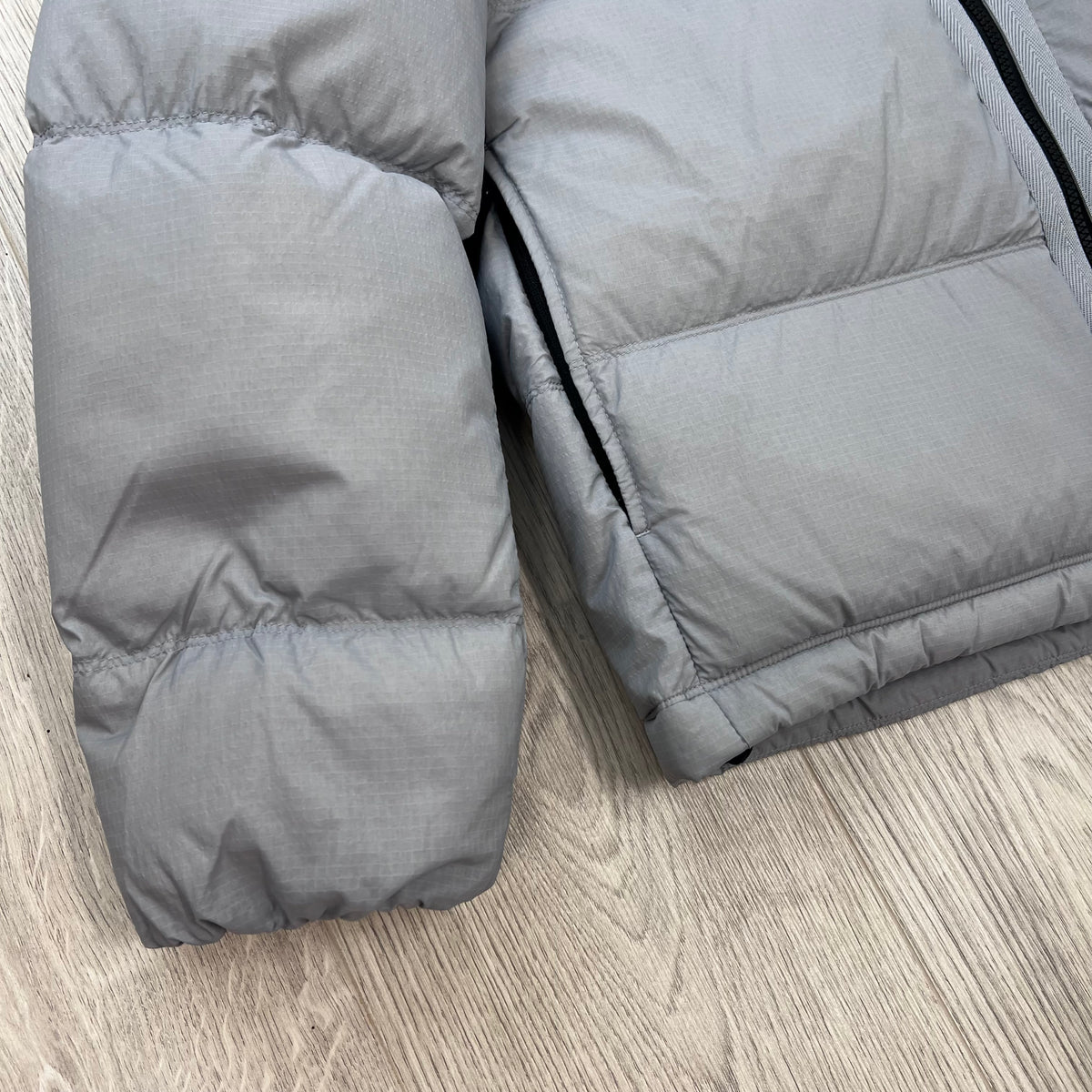 Close up view of the cuff and hem on a Stone Island Matt Ripstop CORDURA® Down Jacket in Ash Grey.