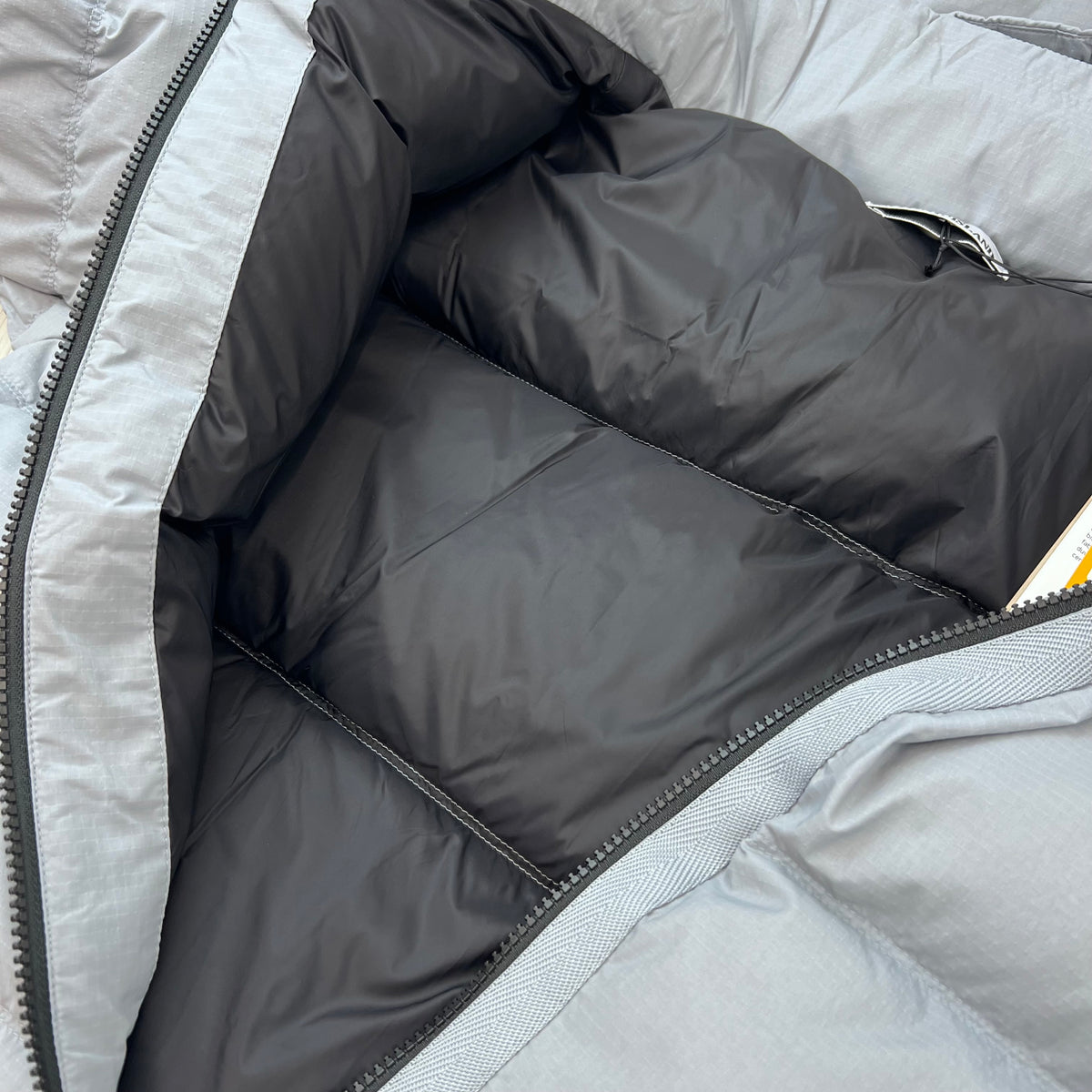 A close up view of the quilting inside a Stone Island Matt Ripstop CORDURA® Down Jacket in Ash Grey.