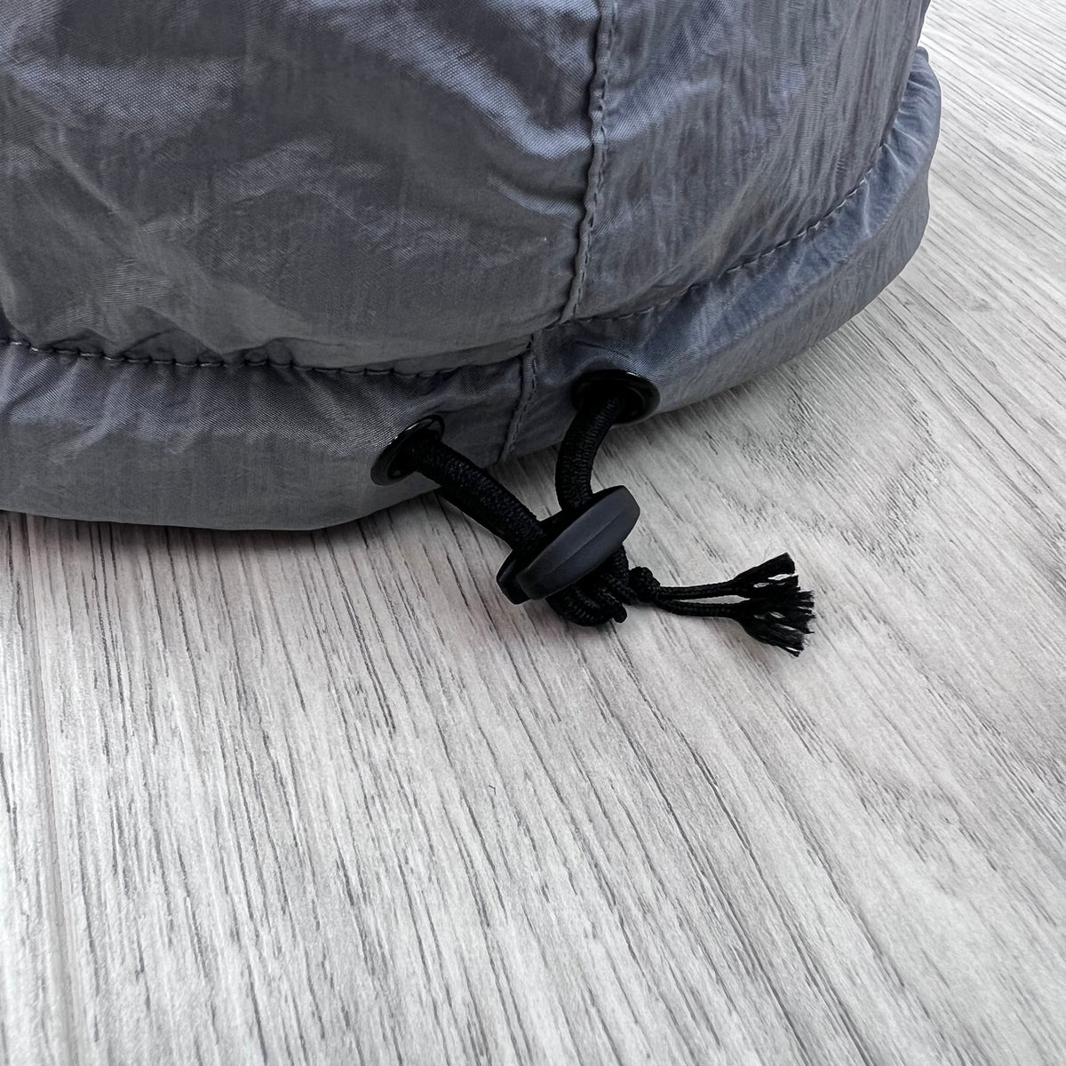 Close up view of the adjustable toggle on a Stone Island Nylon Metal Baseball Cap in Ash Grey.