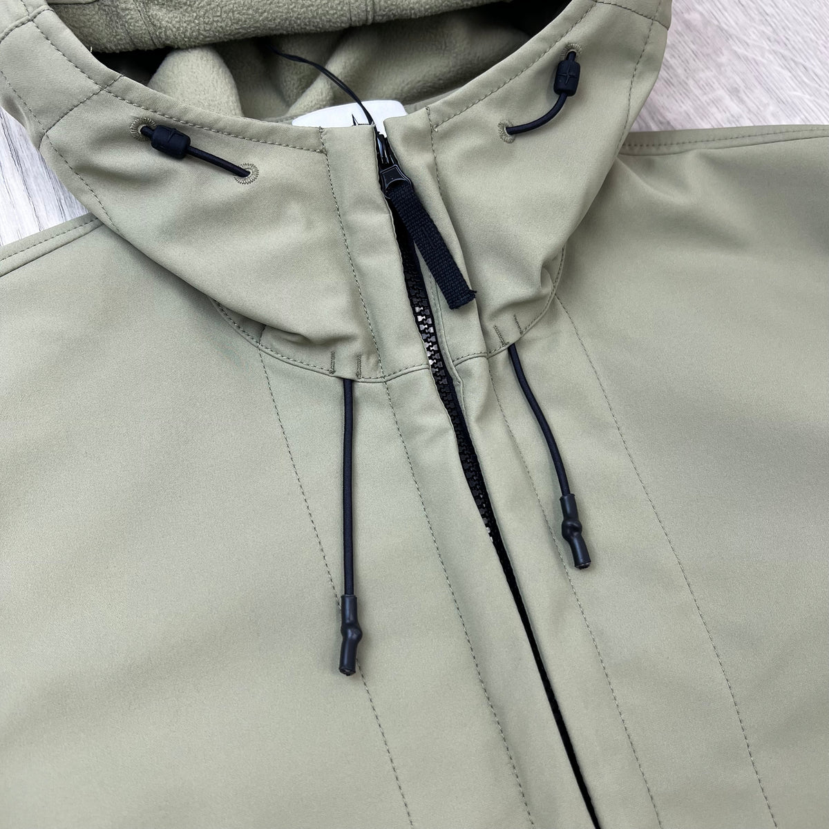A close up view of the zip closure on a Stone Island Soft Shell-R_e.dye® Jacket in Laurel Green.
